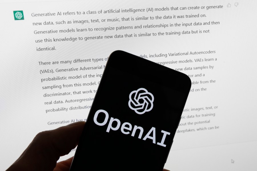 OpenAI logo on a smartphone with ChatGPT output on a computer screen